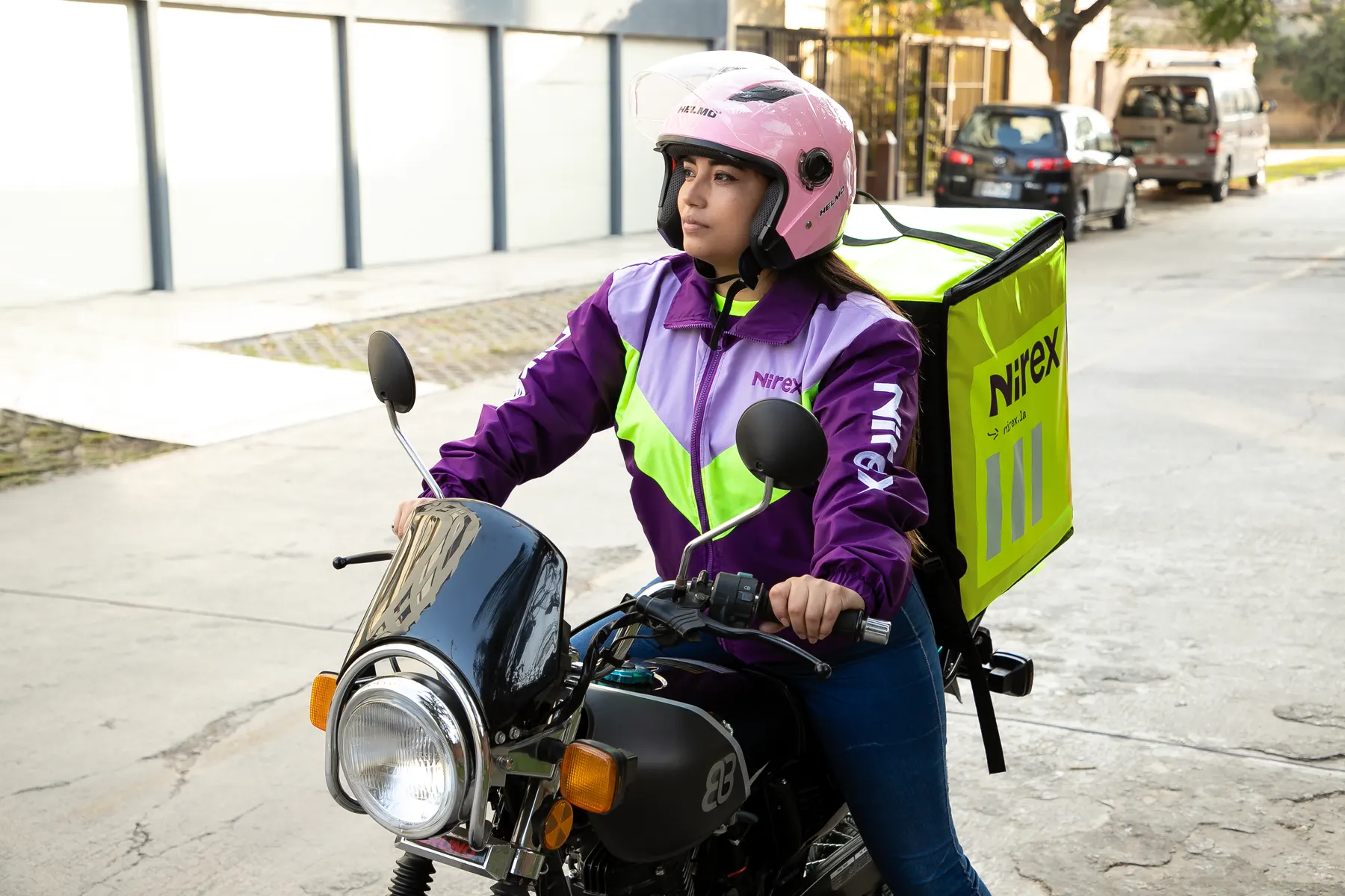 Repartidora de Nirex en moto con caja de reparto, lista para salir a entregar en Lima